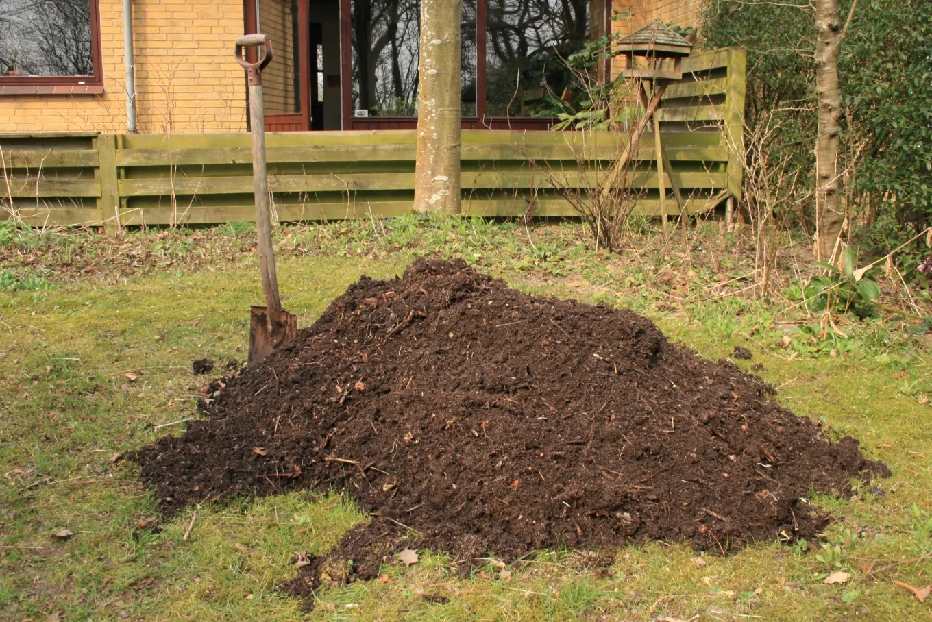A backyard compost heap of dark, finished garden and kitchen compost ready to spread on beds.